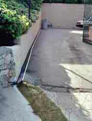 Gray water from a washer runs down a pipe into the street in a wealthy neighborhood in Los Angeles.